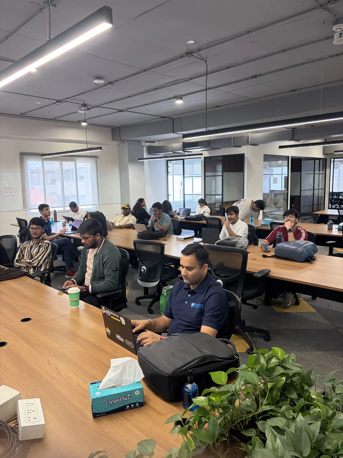 Attendees at long desks with laptops open in a Bengaluru coworking office